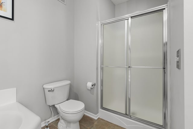 bathroom featuring tile patterned floors, a shower stall, toilet, and baseboards