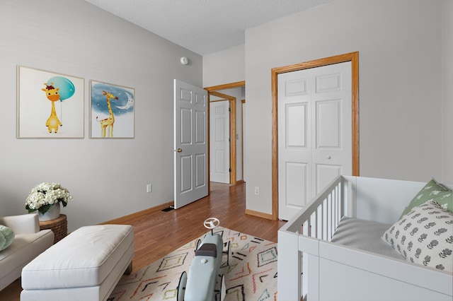 bedroom featuring a textured ceiling, baseboards, and wood finished floors