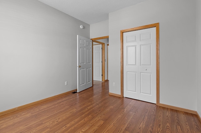 unfurnished bedroom featuring baseboards, a textured ceiling, and wood finished floors