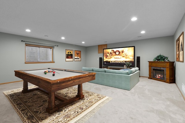 recreation room featuring light carpet, recessed lighting, a warm lit fireplace, and baseboards