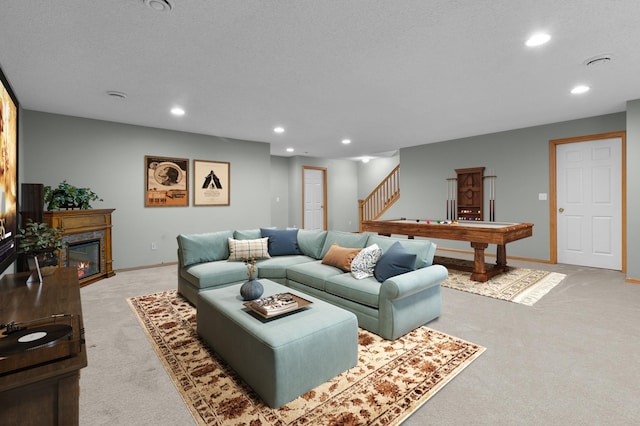 living room featuring stairs, a glass covered fireplace, recessed lighting, and light carpet