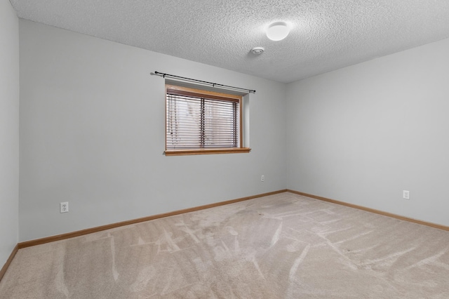 spare room featuring a textured ceiling, baseboards, and carpet