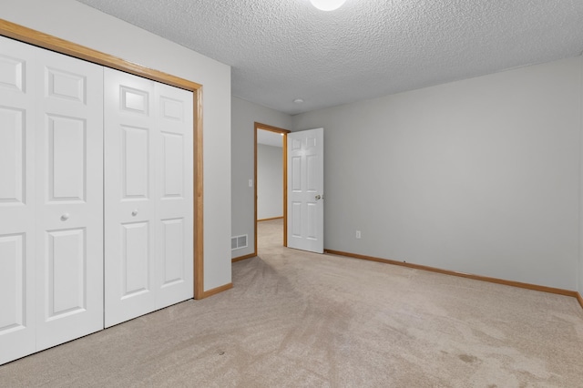 unfurnished bedroom with baseboards, visible vents, carpet floors, a closet, and a textured ceiling