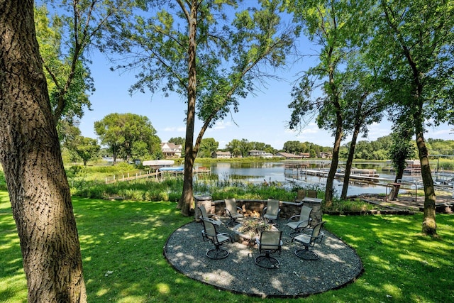 view of green lawn featuring a water view and a fire pit