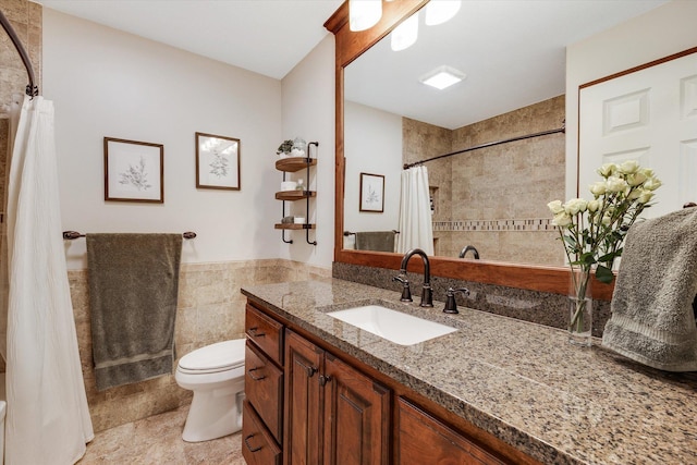 bathroom featuring tile walls, toilet, vanity, curtained shower, and wainscoting