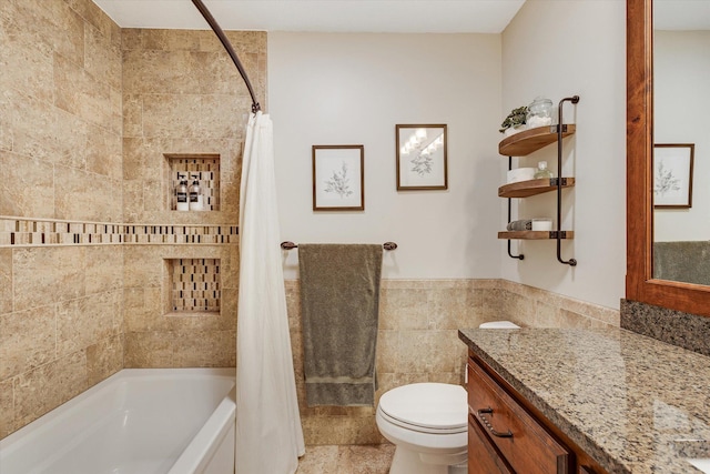 full bathroom featuring tile walls, toilet, shower / bath combination with curtain, vanity, and a wainscoted wall