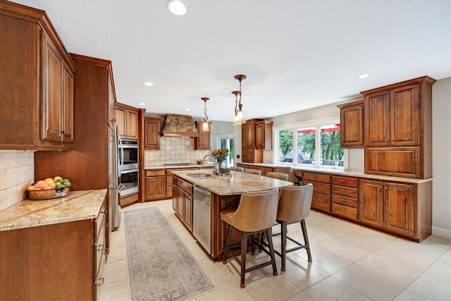 kitchen featuring decorative backsplash, a center island with sink, a sink, a kitchen breakfast bar, and appliances with stainless steel finishes