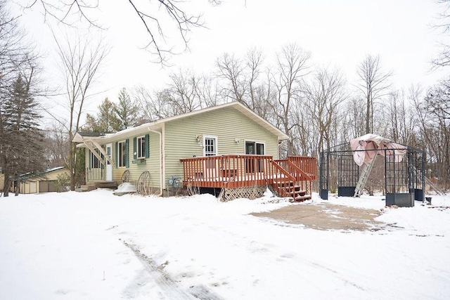 snow covered house featuring a wooden deck