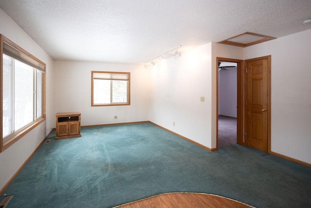 carpeted spare room with a textured ceiling and baseboards