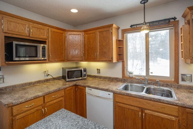 kitchen featuring a wealth of natural light, white dishwasher, stainless steel microwave, and a sink