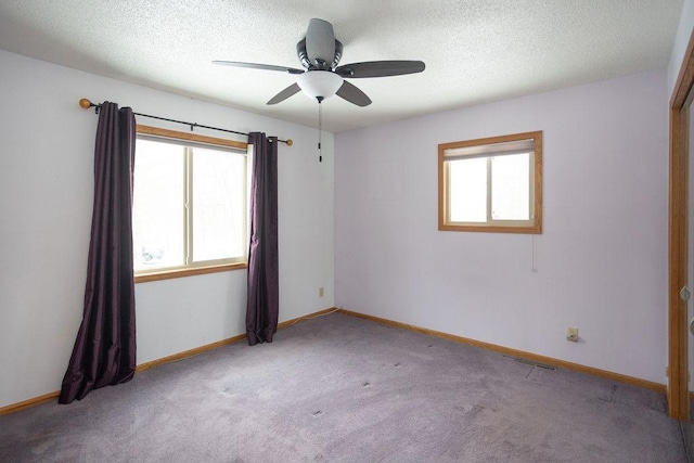 empty room with carpet, baseboards, ceiling fan, and a textured ceiling