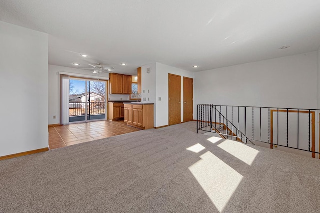 unfurnished living room featuring ceiling fan, light tile patterned flooring, recessed lighting, light colored carpet, and baseboards