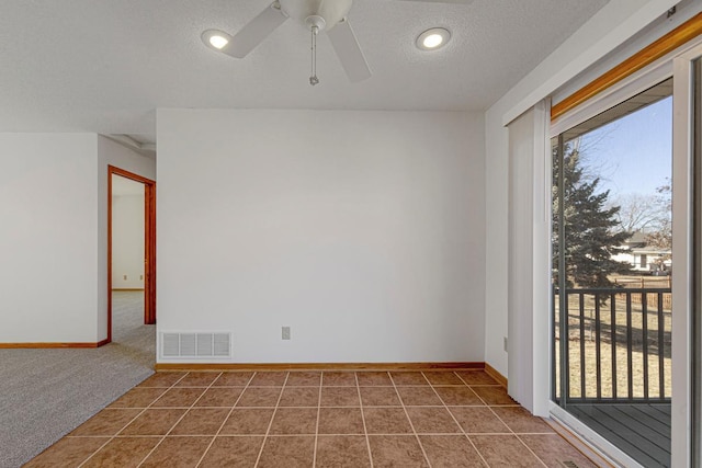 carpeted empty room with baseboards, tile patterned flooring, visible vents, and a textured ceiling