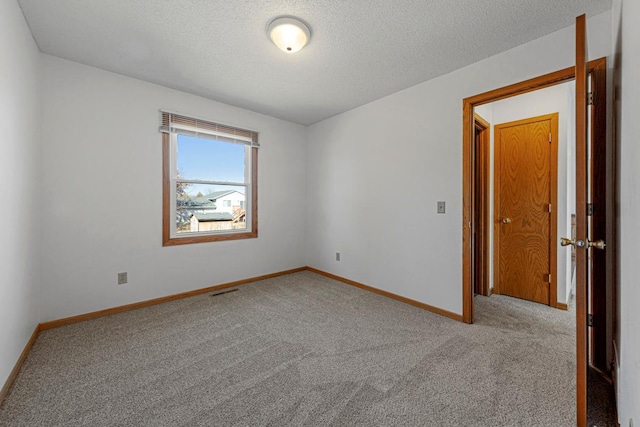 empty room with carpet, visible vents, baseboards, and a textured ceiling