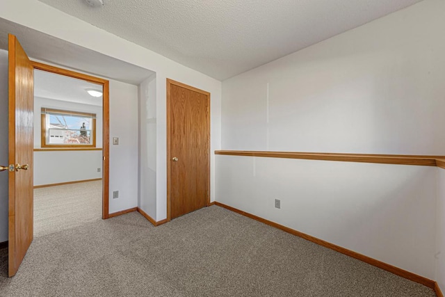 unfurnished bedroom featuring carpet, a closet, baseboards, and a textured ceiling