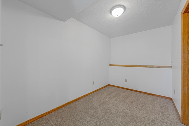 carpeted spare room with baseboards and a textured ceiling