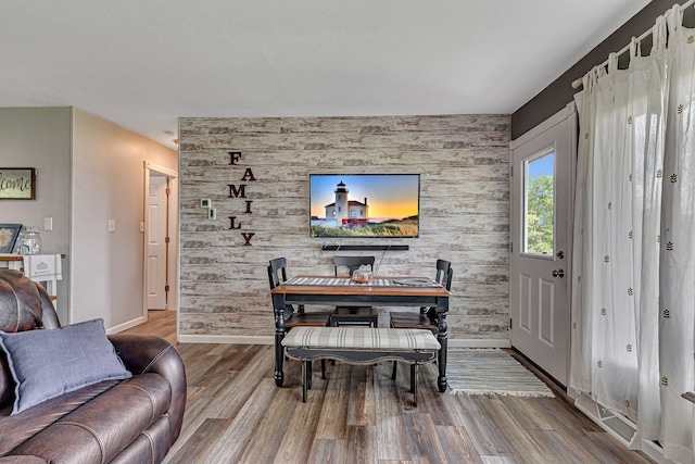 dining space featuring an accent wall, wood finished floors, and baseboards