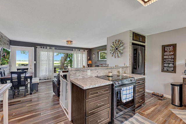 kitchen with tasteful backsplash, wood finished floors, stainless steel appliances, baseboards, and dark brown cabinets