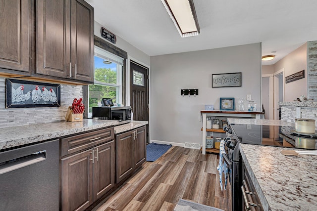 kitchen featuring stainless steel appliances, backsplash, dark brown cabinets, and dark wood finished floors