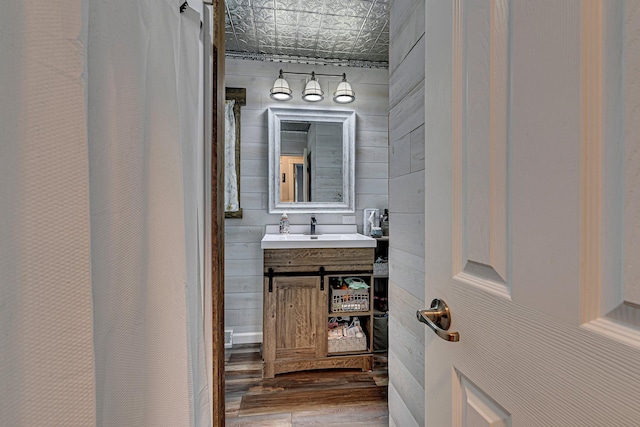 full bathroom featuring wood finished floors, an ornate ceiling, wood walls, and vanity