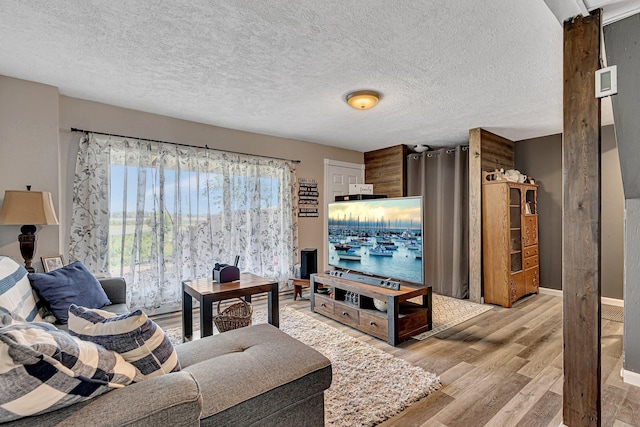 living room with baseboards, a textured ceiling, and light wood-style floors