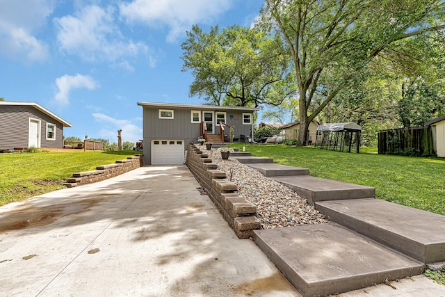 view of front of house featuring an attached garage, concrete driveway, a front lawn, and fence