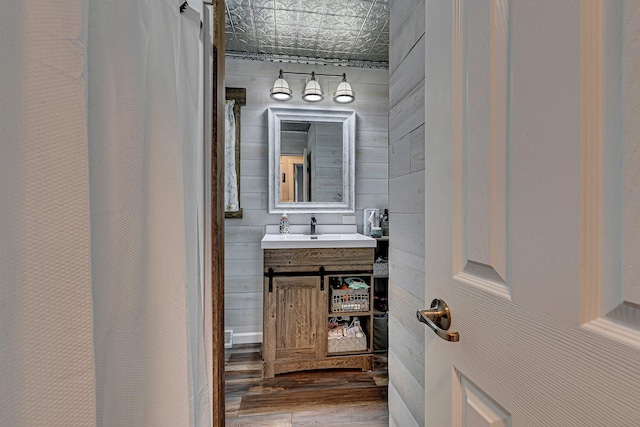 full bath with an ornate ceiling, wooden walls, wood finished floors, and vanity