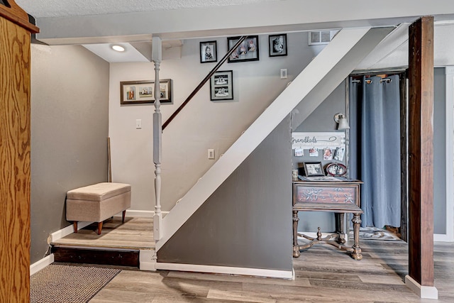stairway featuring visible vents, baseboards, and wood finished floors