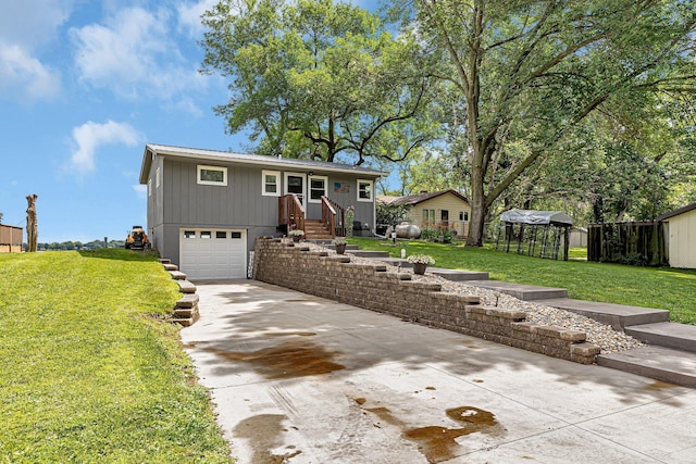 view of front of home with an attached garage, concrete driveway, a front lawn, and fence