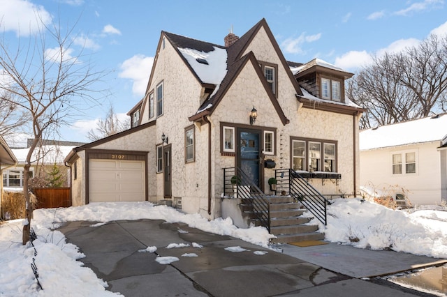 view of front of home featuring stone siding, stucco siding, an attached garage, and fence