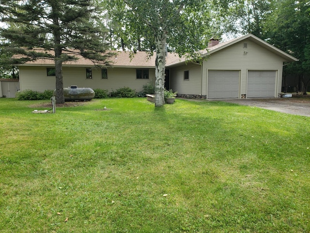 ranch-style home with a garage, driveway, a chimney, and a front yard