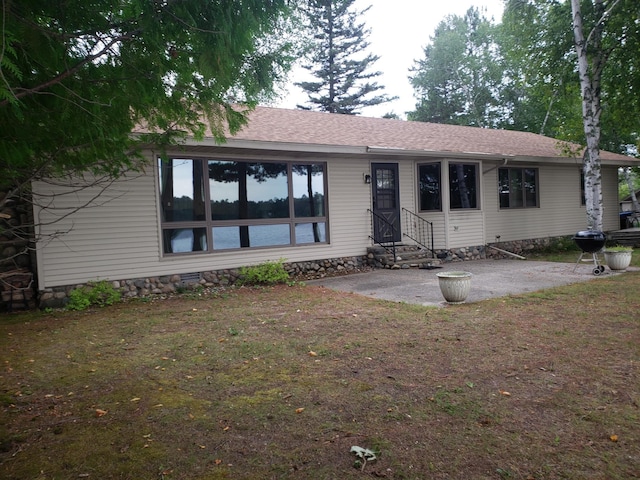 single story home featuring crawl space, roof with shingles, a patio, and a front lawn