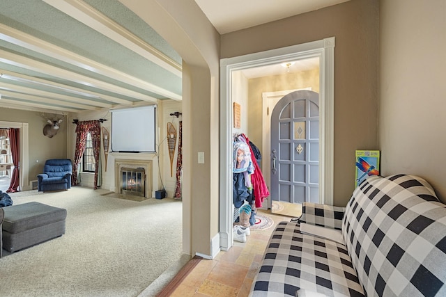 interior space with a fireplace with flush hearth, arched walkways, baseboards, and light colored carpet