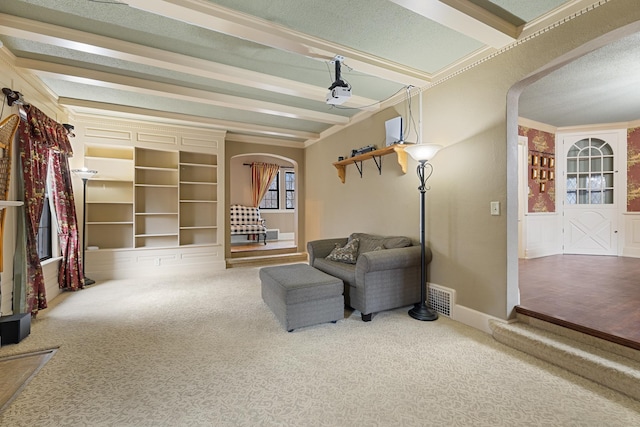 sitting room with arched walkways, beamed ceiling, carpet flooring, and visible vents