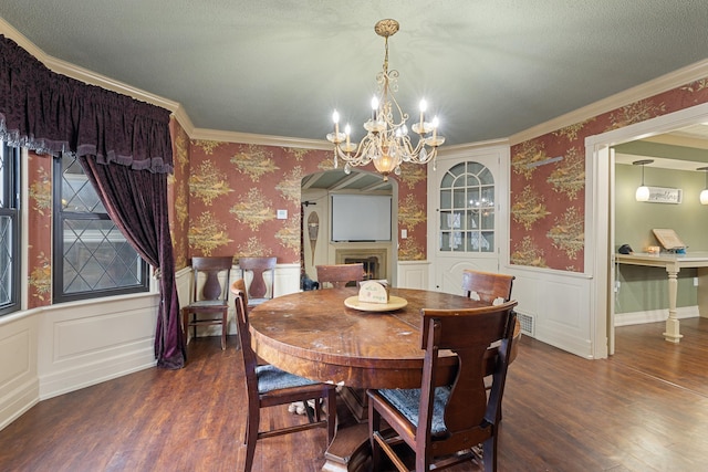 dining space featuring wainscoting, a fireplace, wood finished floors, and wallpapered walls