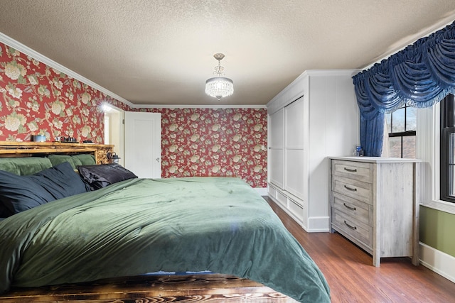 bedroom featuring wallpapered walls, baseboards, ornamental molding, dark wood-type flooring, and a textured ceiling