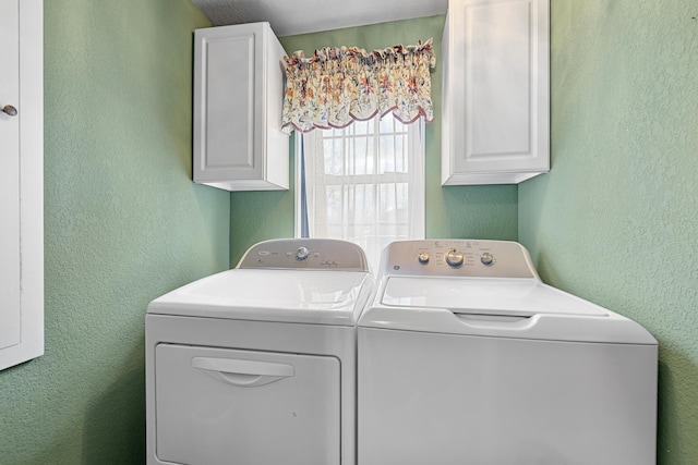 laundry area featuring cabinet space, washer and clothes dryer, and a textured wall