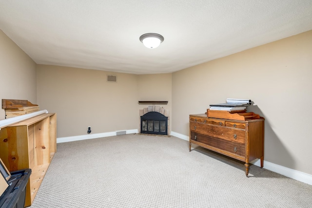 interior space featuring light carpet, baseboards, visible vents, and a glass covered fireplace