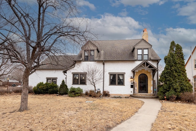 tudor house featuring a shingled roof and a chimney