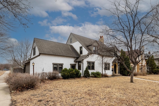 view of front of home with a garage, a chimney, and roof with shingles