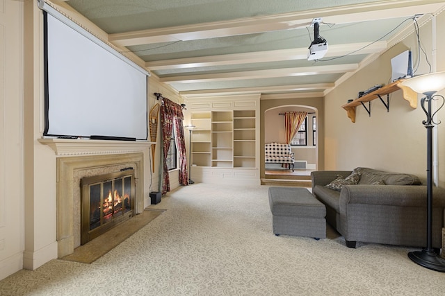 living room featuring carpet, a fireplace with flush hearth, arched walkways, and beam ceiling