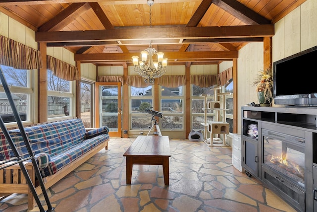 living room with lofted ceiling with beams, a healthy amount of sunlight, wooden walls, and a notable chandelier