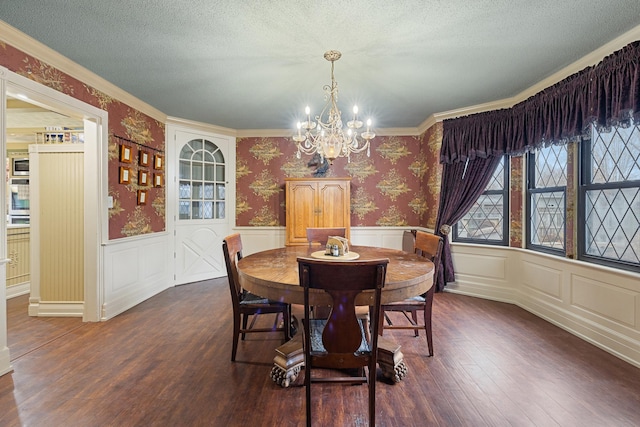 dining room featuring wallpapered walls, wainscoting, dark wood-style flooring, a textured ceiling, and a chandelier