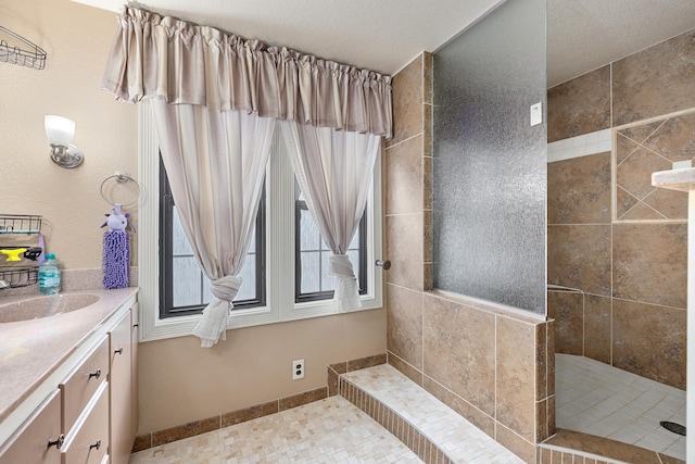 bathroom with baseboards, a walk in shower, and vanity