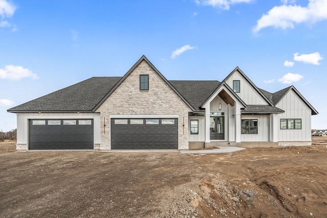 modern farmhouse featuring a garage, dirt driveway, a shingled roof, and board and batten siding