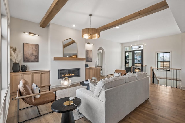 living room with baseboards, wood finished floors, beam ceiling, and a glass covered fireplace