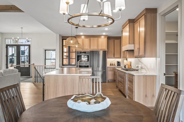 kitchen with stainless steel appliances, light wood-type flooring, a chandelier, and light countertops