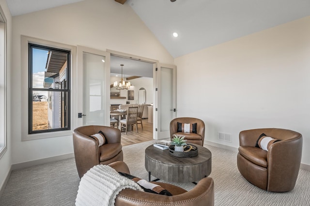 living area with an inviting chandelier, baseboards, visible vents, and high vaulted ceiling