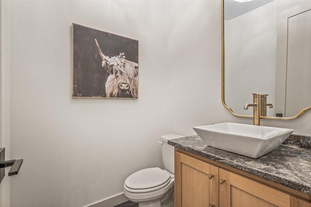 bathroom with vanity, toilet, and baseboards