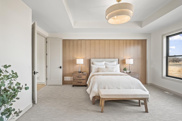 carpeted bedroom featuring a raised ceiling, visible vents, and baseboards